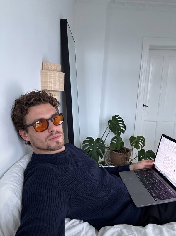Man reclining with a laptop wearing Skopos amber focus glasses