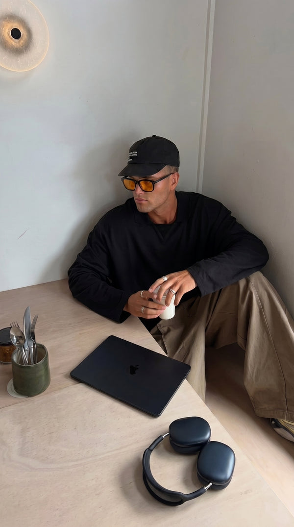 Man sitting on the floor with a laptop and headphones wearing Skopos amber focus glasses